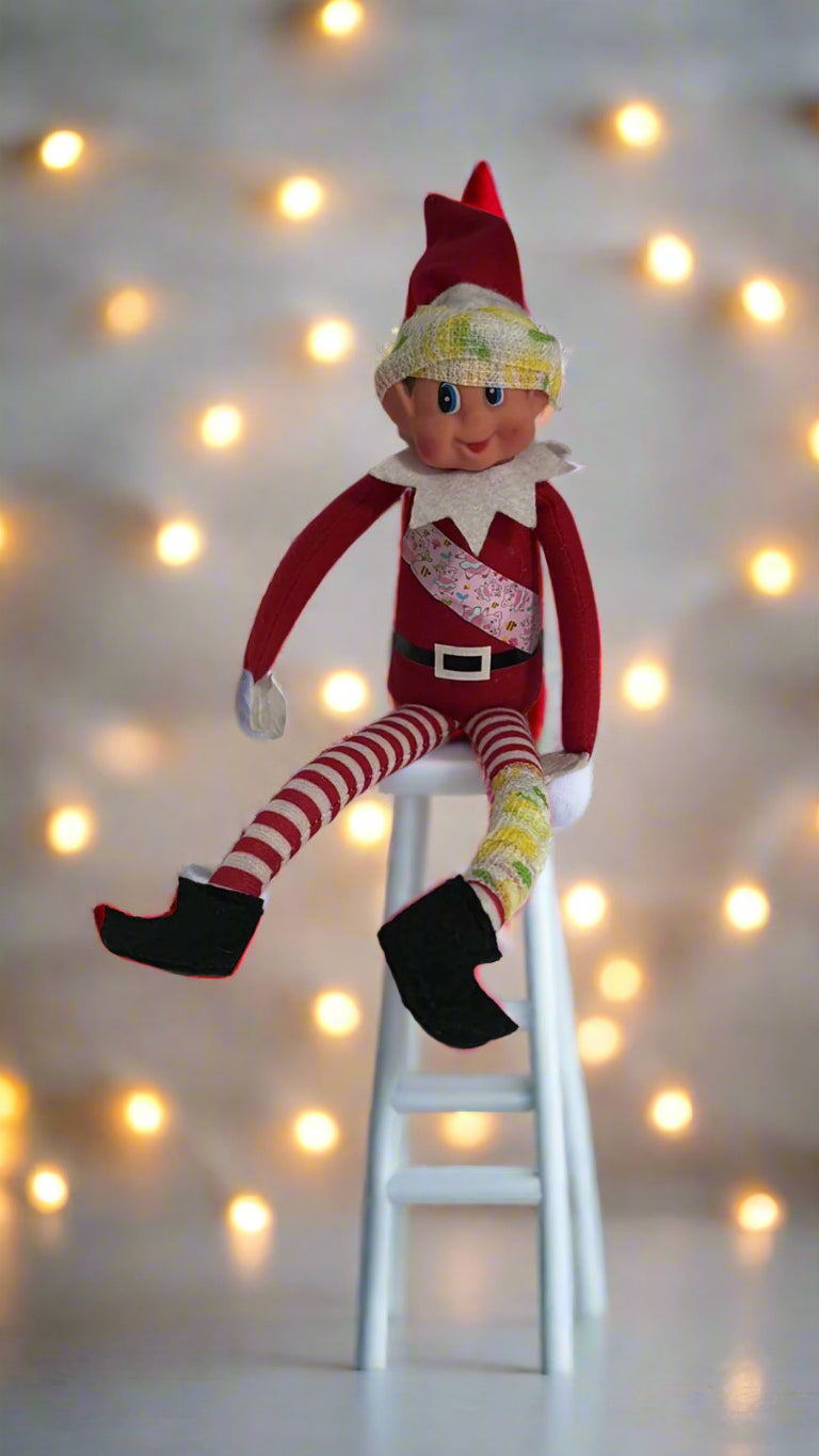 Elf doll sitting on a stool with string lights—holiday display prop for the activity boxes