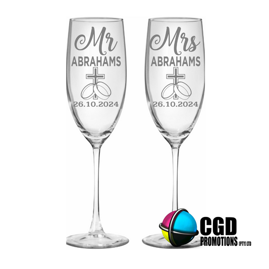 “Personalized champagne flutes with cross and wedding rings design – Mr & Mrs glasses engraved with surname and date”


