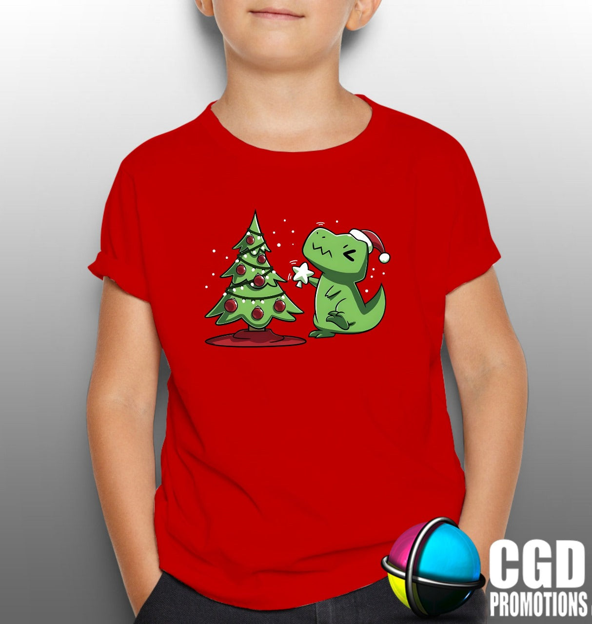 Kids red Christmas T-shirt with cartoon dinosaur decorating a Christmas tree.